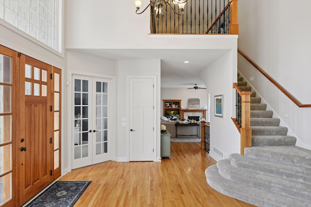 foyer with french doors, stairs, a lit fireplace, and wood finished floors