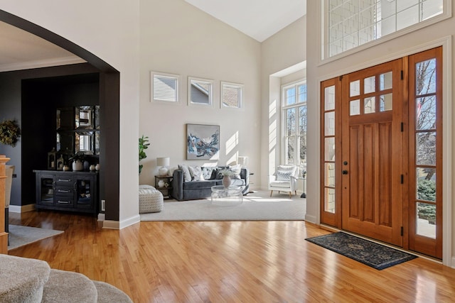 foyer entrance with arched walkways, wood finished floors, and a towering ceiling