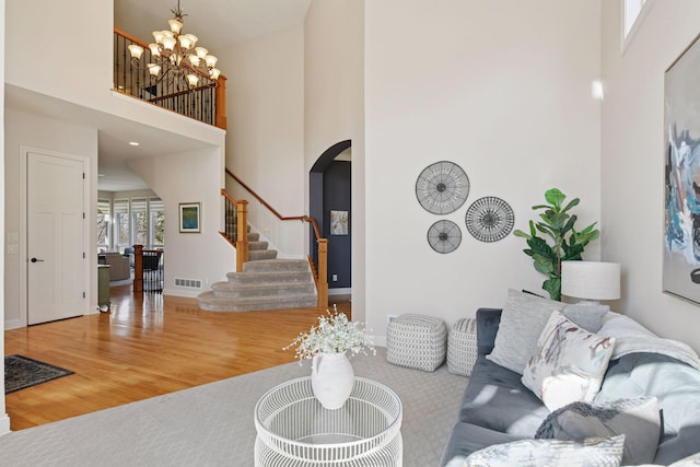 living room with visible vents, wood finished floors, stairway, a high ceiling, and a chandelier