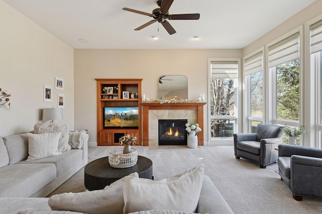 living room with carpet flooring, ceiling fan, a tile fireplace, and built in shelves