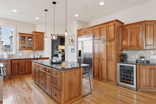 kitchen with light wood finished floors, a kitchen island, wine cooler, built in fridge, and brown cabinets