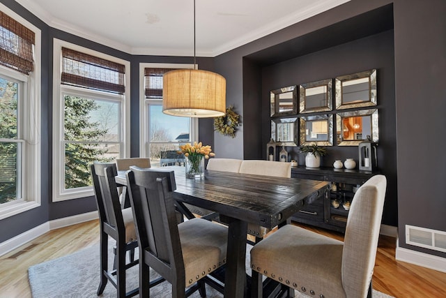 dining room featuring visible vents, wood finished floors, and crown molding