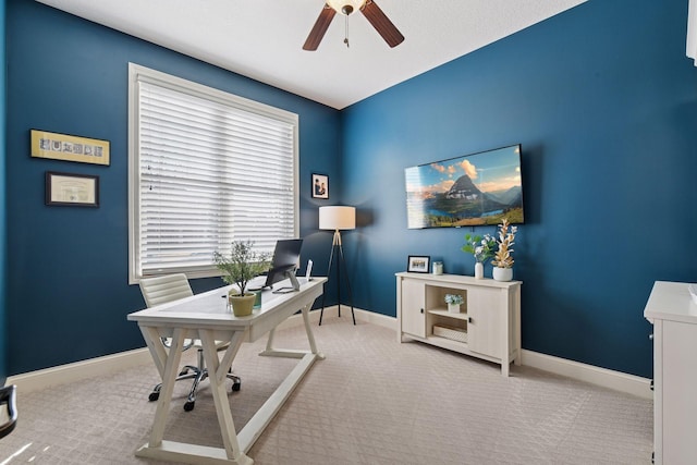 carpeted office space with baseboards and ceiling fan