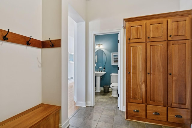 interior space with tile patterned floors, toilet, baseboards, and a sink