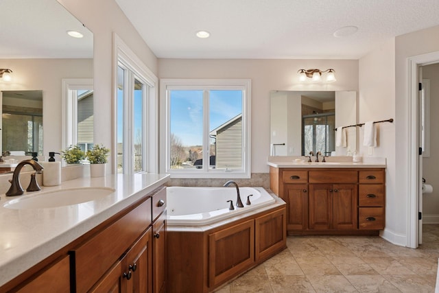 full bath featuring a stall shower, two vanities, a garden tub, and a sink