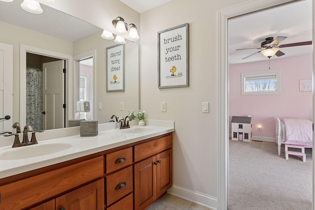 full bathroom featuring double vanity, a ceiling fan, baseboards, and a sink