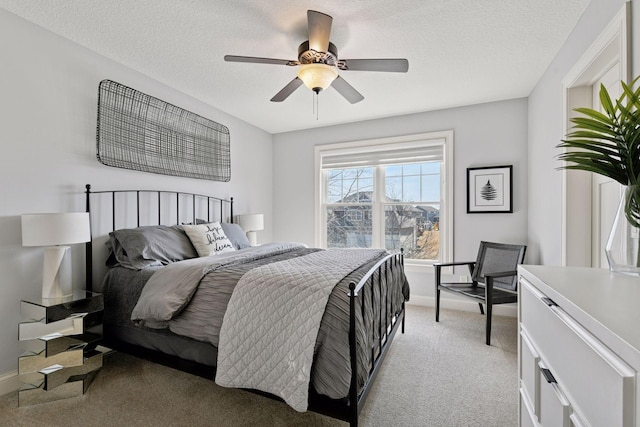 bedroom featuring light carpet, ceiling fan, a textured ceiling, and baseboards