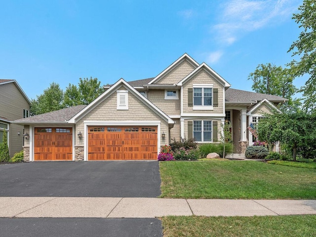 craftsman-style home with a garage, driveway, a front lawn, and stone siding