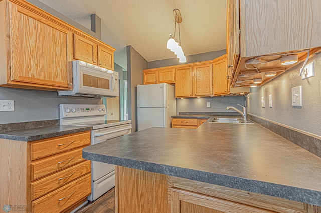 kitchen with a sink, dark countertops, a textured ceiling, white appliances, and a peninsula