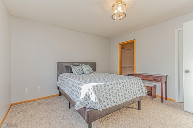 carpeted bedroom with baseboards, a textured ceiling, and a spacious closet