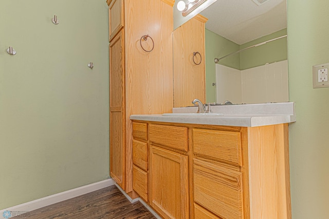 bathroom with vanity, wood finished floors, and baseboards