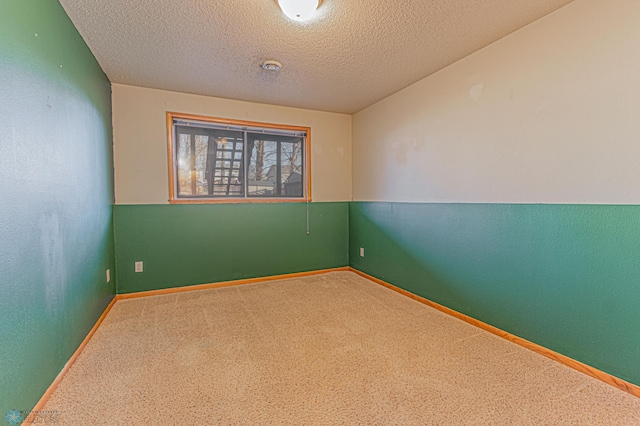 carpeted spare room with baseboards and a textured ceiling