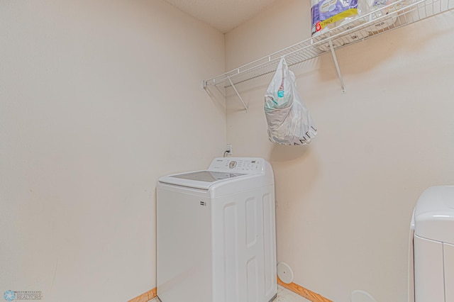 washroom featuring laundry area, washer / clothes dryer, and baseboards