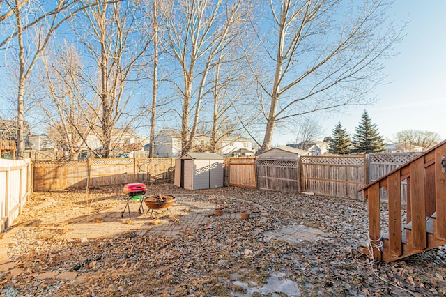 view of yard with an outbuilding, a shed, an outdoor fire pit, and a fenced backyard