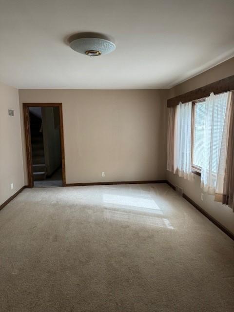 unfurnished room featuring stairway, baseboards, and light carpet