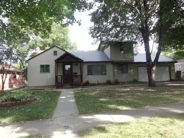 view of front of house featuring a garage, a front lawn, metal roof, and a chimney