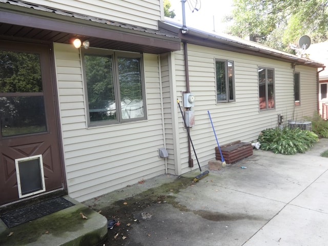 view of side of home featuring metal roof and a patio area