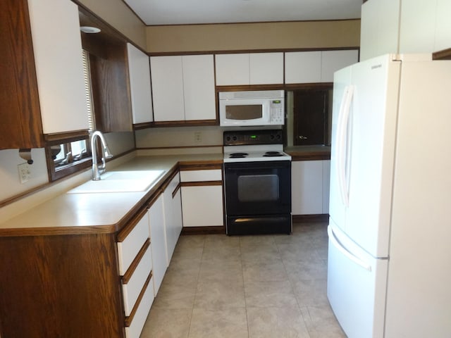 kitchen with a sink, white appliances, white cabinets, and light tile patterned floors