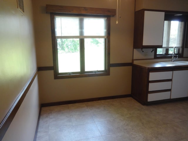 kitchen with white cabinetry, baseboards, and a sink