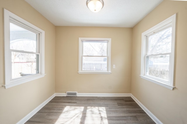 spare room featuring dark wood-type flooring, baseboards, and visible vents