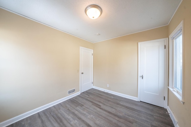 unfurnished room with ornamental molding, wood finished floors, visible vents, and baseboards