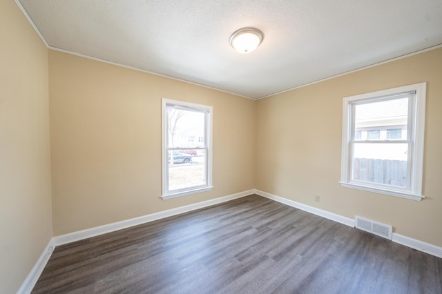 unfurnished room featuring visible vents, baseboards, and dark wood finished floors