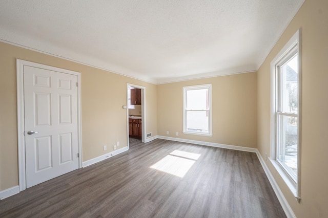 interior space with a wealth of natural light, baseboards, a textured ceiling, and dark wood finished floors