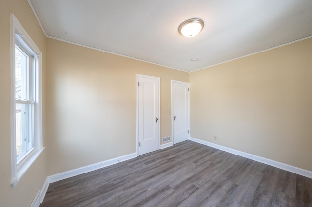 unfurnished room featuring visible vents, ornamental molding, baseboards, and dark wood-style flooring