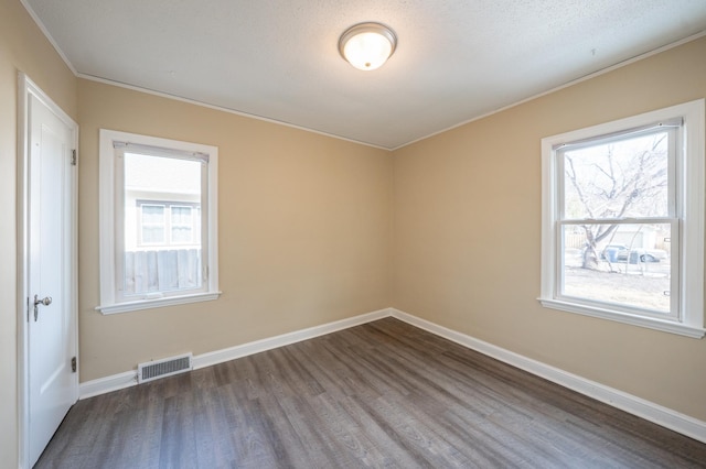 unfurnished room with visible vents, crown molding, baseboards, and dark wood-style flooring