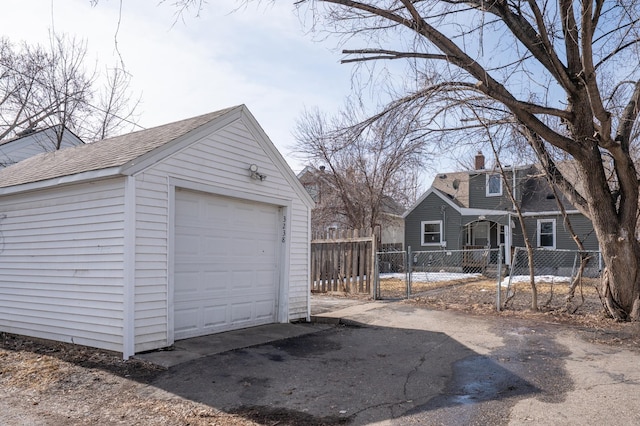 detached garage with a gate, aphalt driveway, and fence