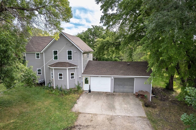 traditional-style house with a garage, a front yard, driveway, and a shingled roof