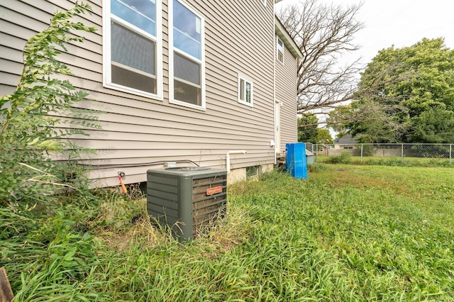 view of side of home featuring cooling unit, a yard, and fence