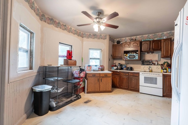 kitchen with wooden walls, light floors, white appliances, and light countertops