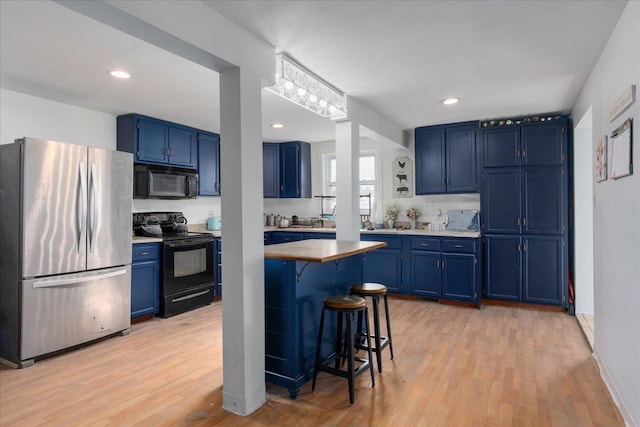 kitchen with black appliances, blue cabinetry, light countertops, and a kitchen breakfast bar