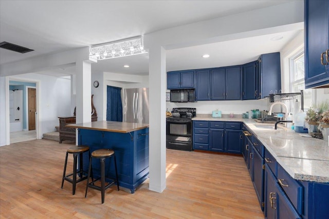 kitchen with black appliances, blue cabinetry, visible vents, and light wood finished floors