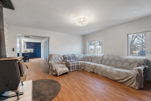 living room featuring visible vents, light wood-type flooring, and a wood stove