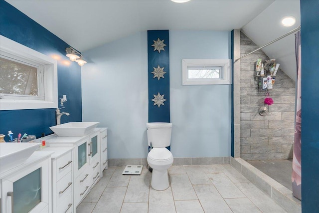 bathroom featuring vaulted ceiling, toilet, tiled shower, and a sink