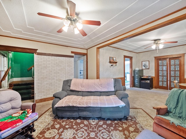 carpeted living area with stairs and a ceiling fan