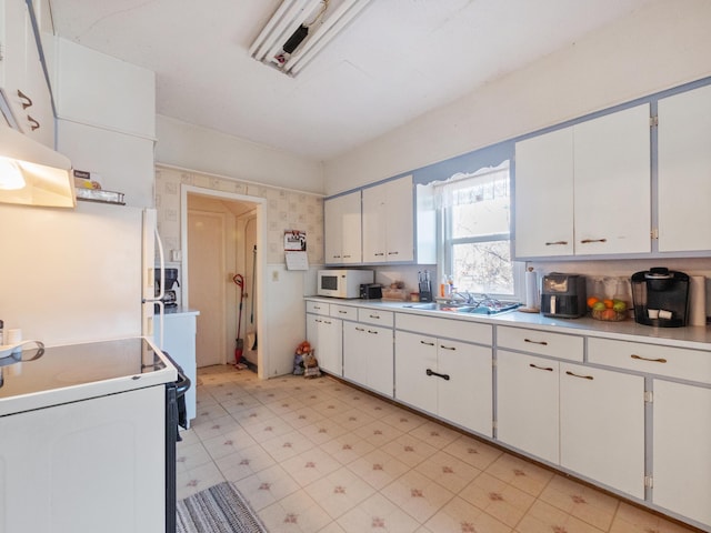 kitchen featuring a sink, white appliances, white cabinetry, and light countertops