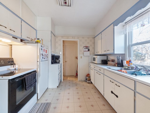 kitchen featuring a sink, white appliances, white cabinets, light countertops, and light floors