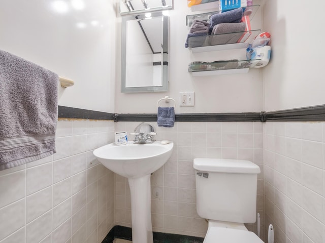 half bath with toilet, tile walls, and wainscoting