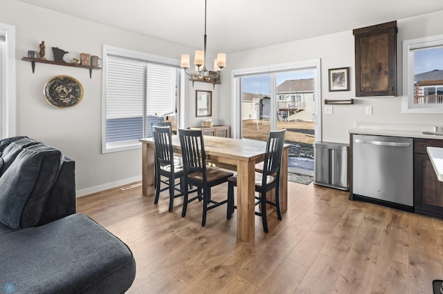 dining area featuring an inviting chandelier, baseboards, and light wood-type flooring