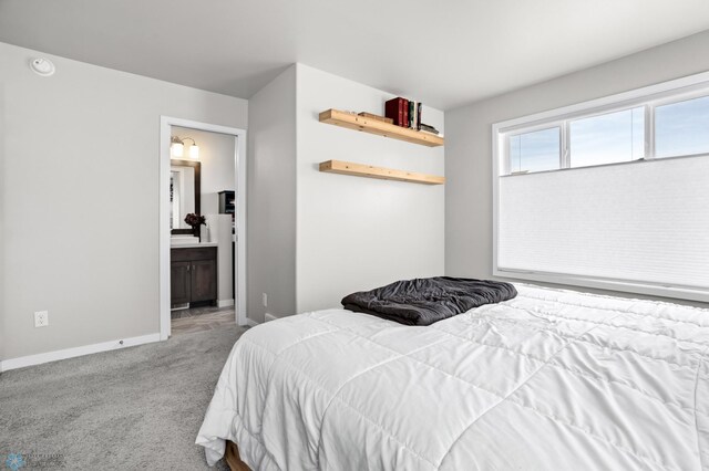 carpeted bedroom with ensuite bath and baseboards