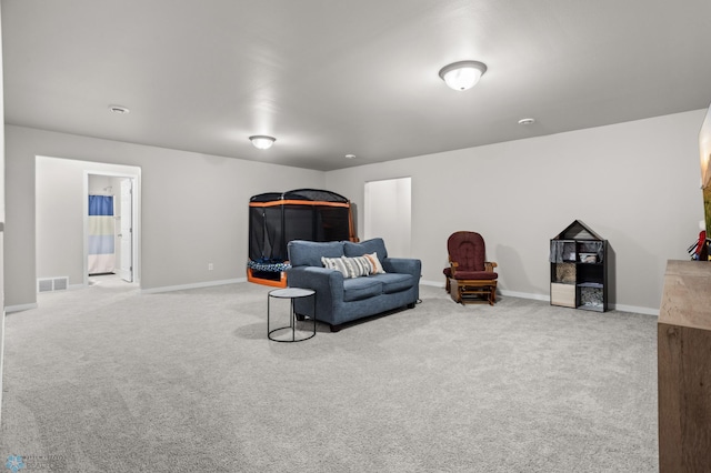 living area with baseboards, visible vents, and carpet floors