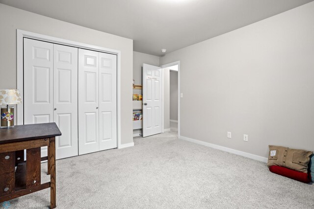 bedroom with light carpet, a closet, and baseboards