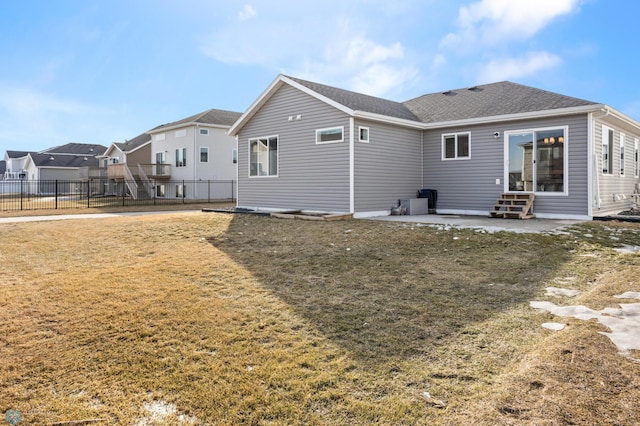 rear view of house featuring a shingled roof, fence, entry steps, a yard, and a patio