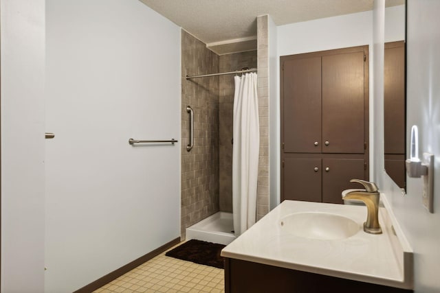 bathroom featuring vanity, baseboards, a stall shower, and a textured ceiling