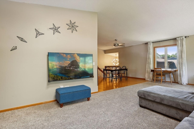 living area featuring baseboards, carpet, and ceiling fan with notable chandelier