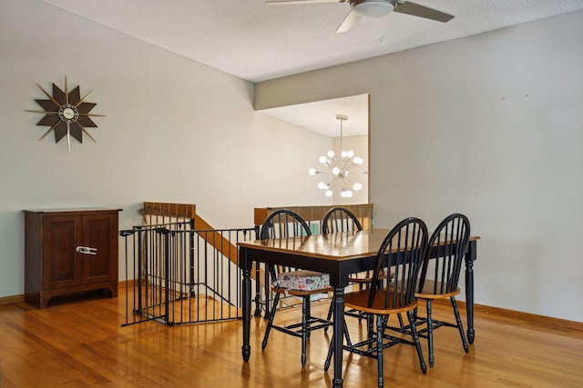 dining space featuring baseboards, a textured ceiling, light wood-style flooring, and ceiling fan with notable chandelier