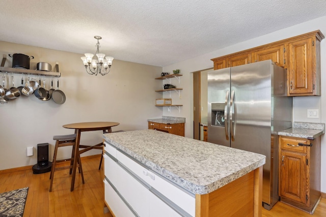 kitchen with open shelves, light wood-style flooring, stainless steel fridge with ice dispenser, light countertops, and a center island